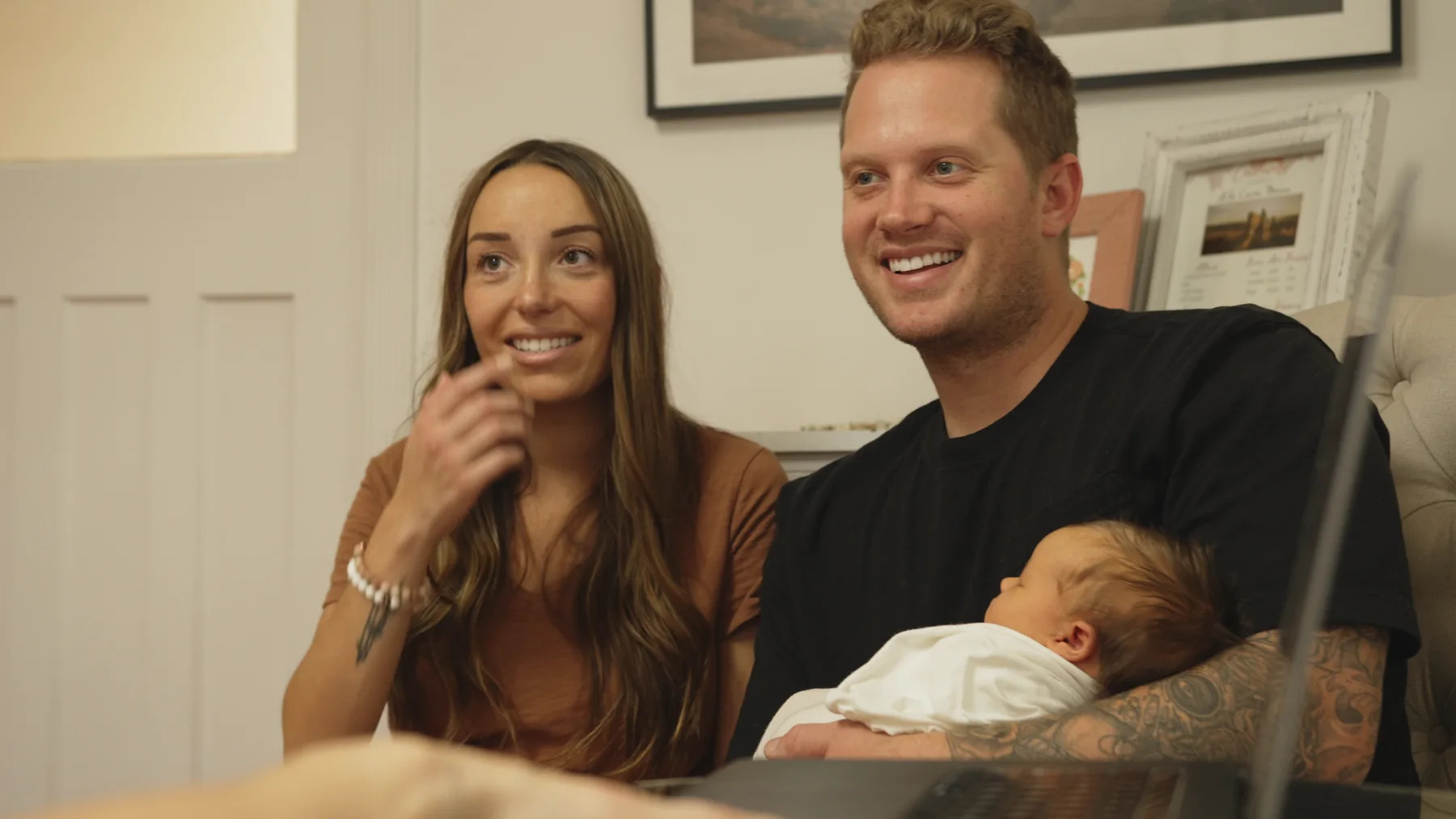 Parents holding a newborn during the Amie Roussel Photography brand video.