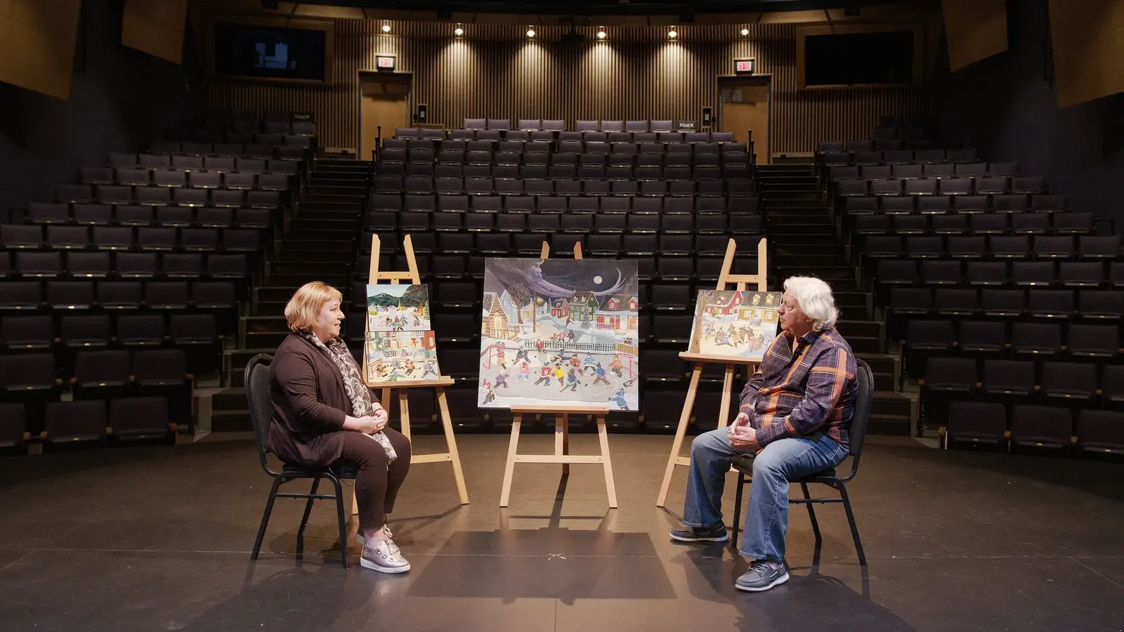 Wide ArtsCO artist interview frame with paintings in a theatre.