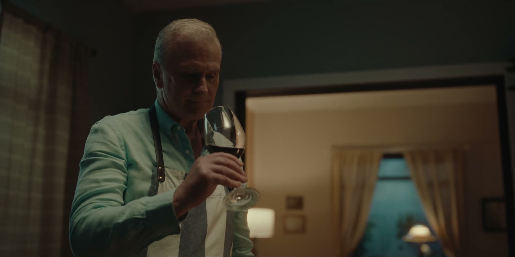 Two men confront one another in a carefully lit apartment interior.