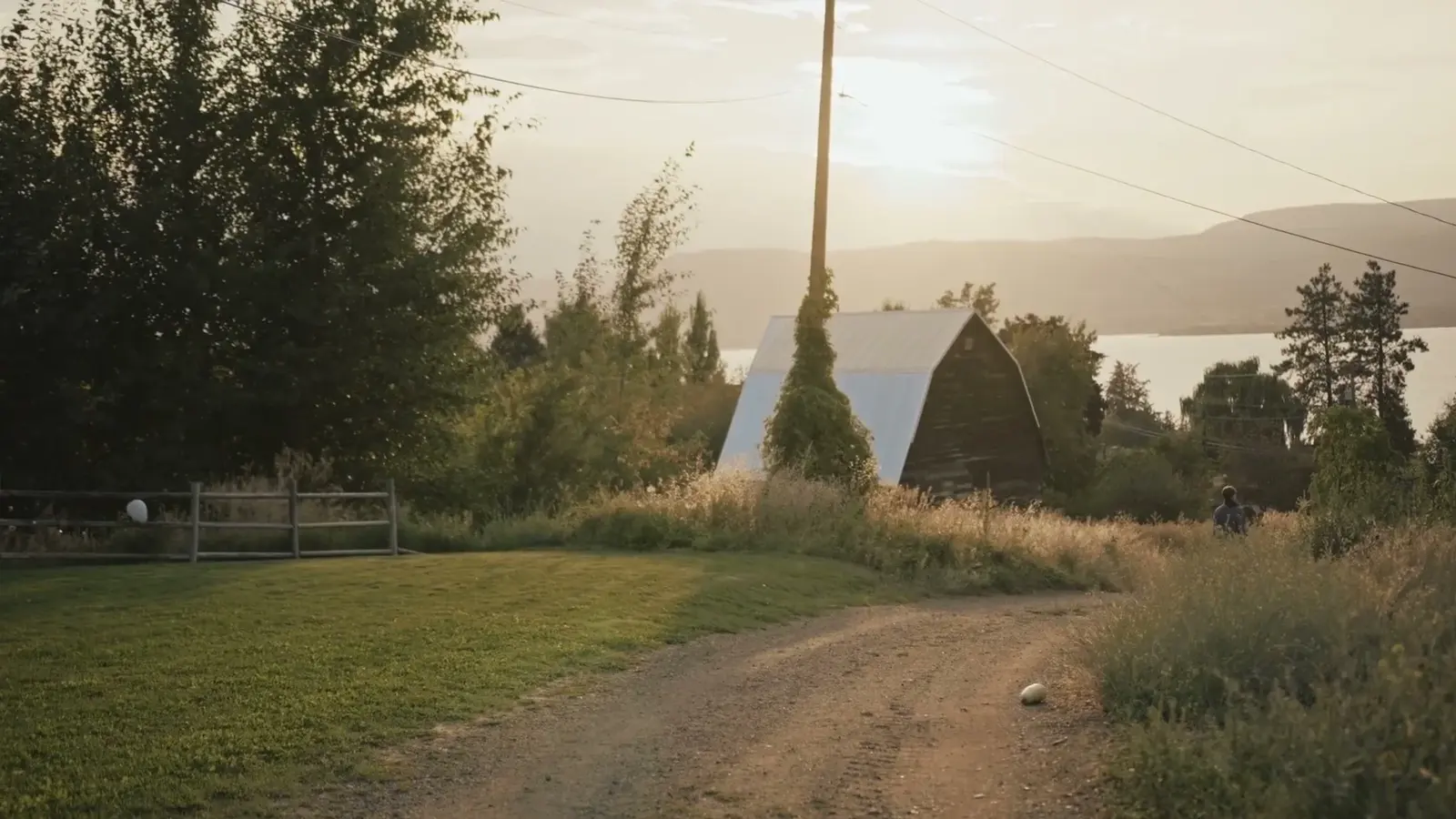 White tipis stand beside a lake in late-day light.