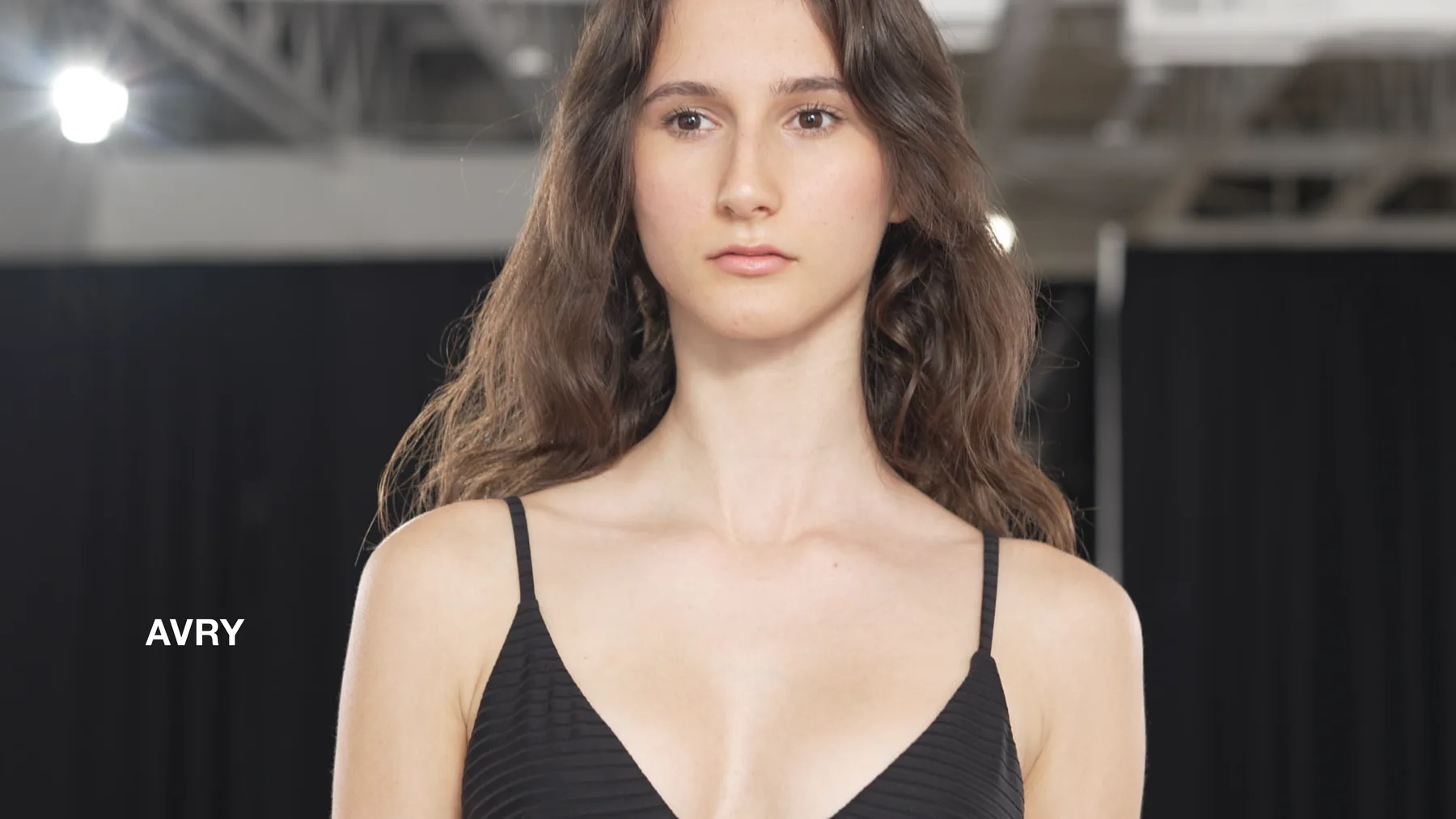 Avry in swimwear with her name on screen during the Deja Vu Model Search.