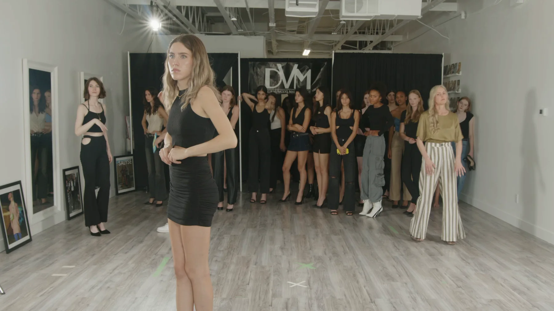 A Deja Vu Model Management group lineup in front of the DVM backdrop during a model-search video shoot.