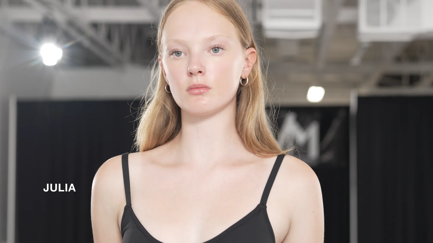 Julia in swimwear with her name on screen during the Deja Vu Model Search.