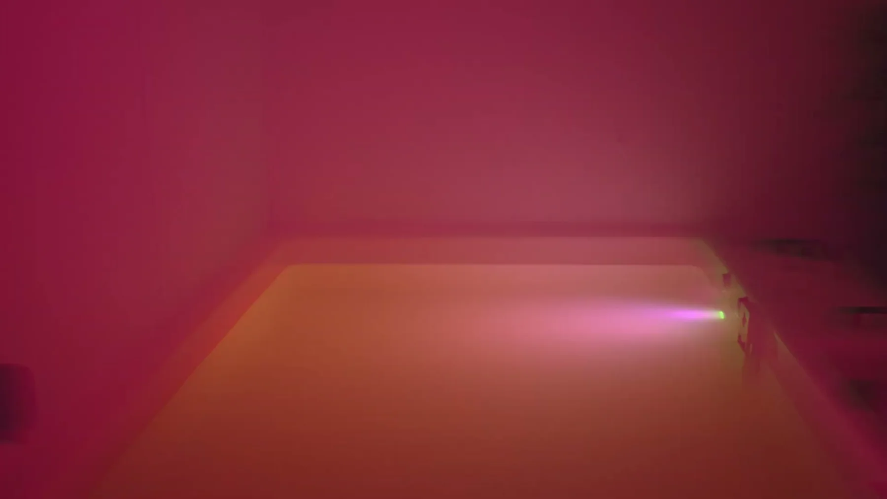 An empty float tank glows with red and violet light.