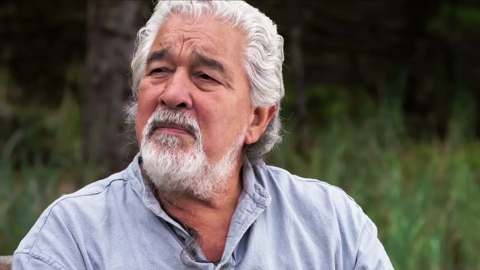 A man speaks outdoors near Haida House at Tllaal.