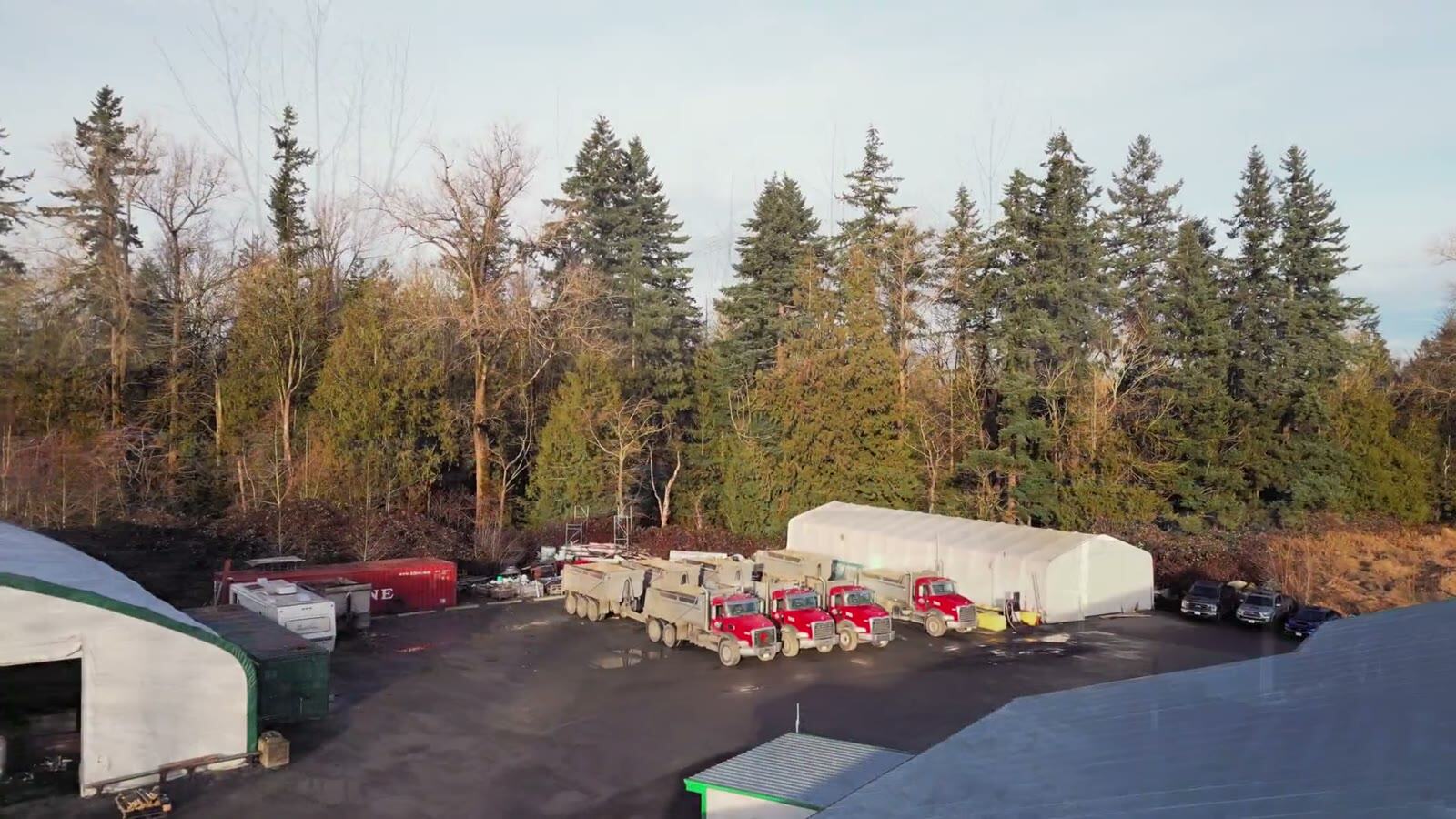 Drone frame looking down on wet construction access lanes and trucks.
