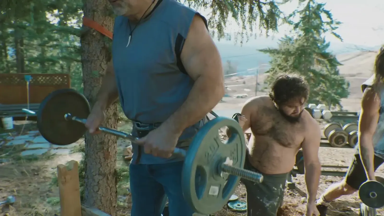 A group lifts weights outdoors among the trees.