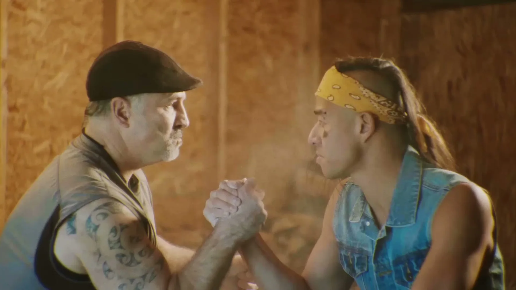 Two men clasp hands across an arm-wrestling table.