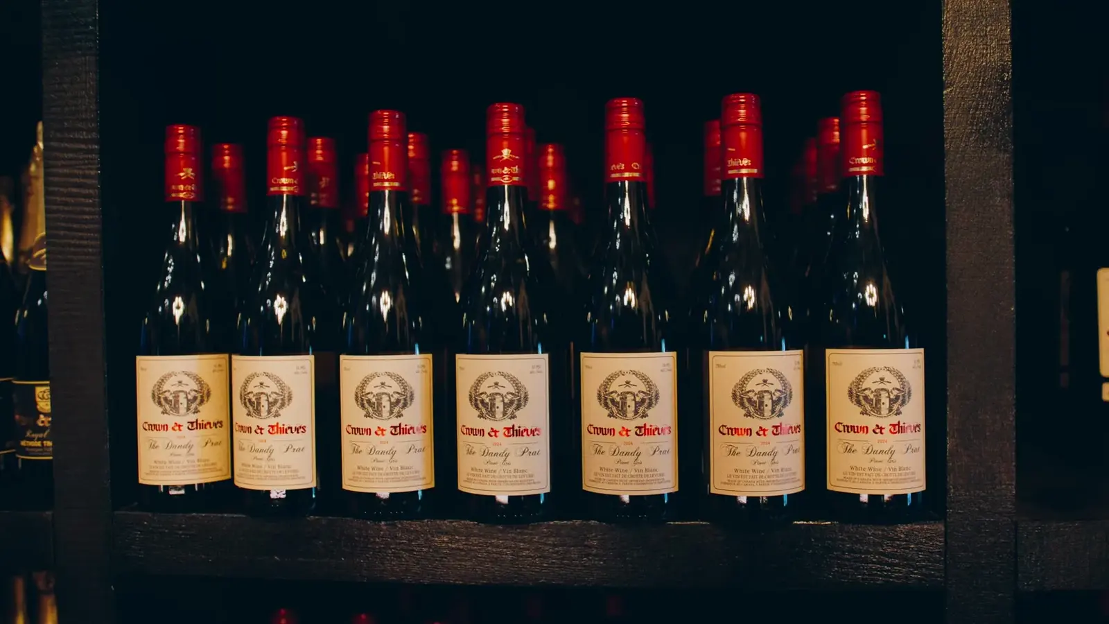 Rows of Crown and Thieves wine bottles in the Jason Parkes Customs commercial.