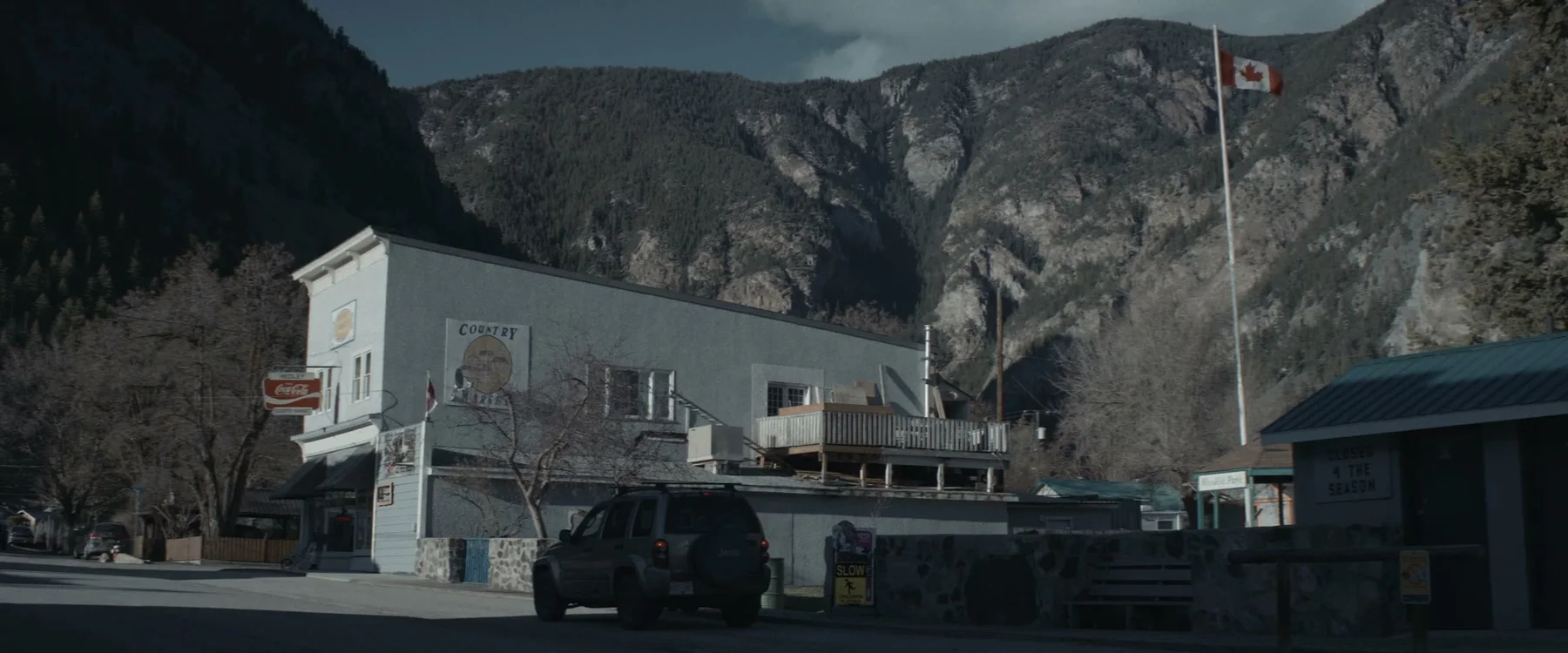 A small-town street sits beneath steep winter mountains.