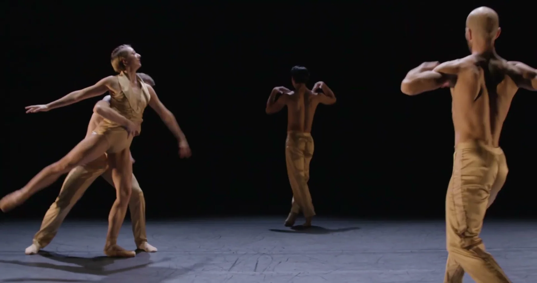 Three dancers move through staggered positions on stage.