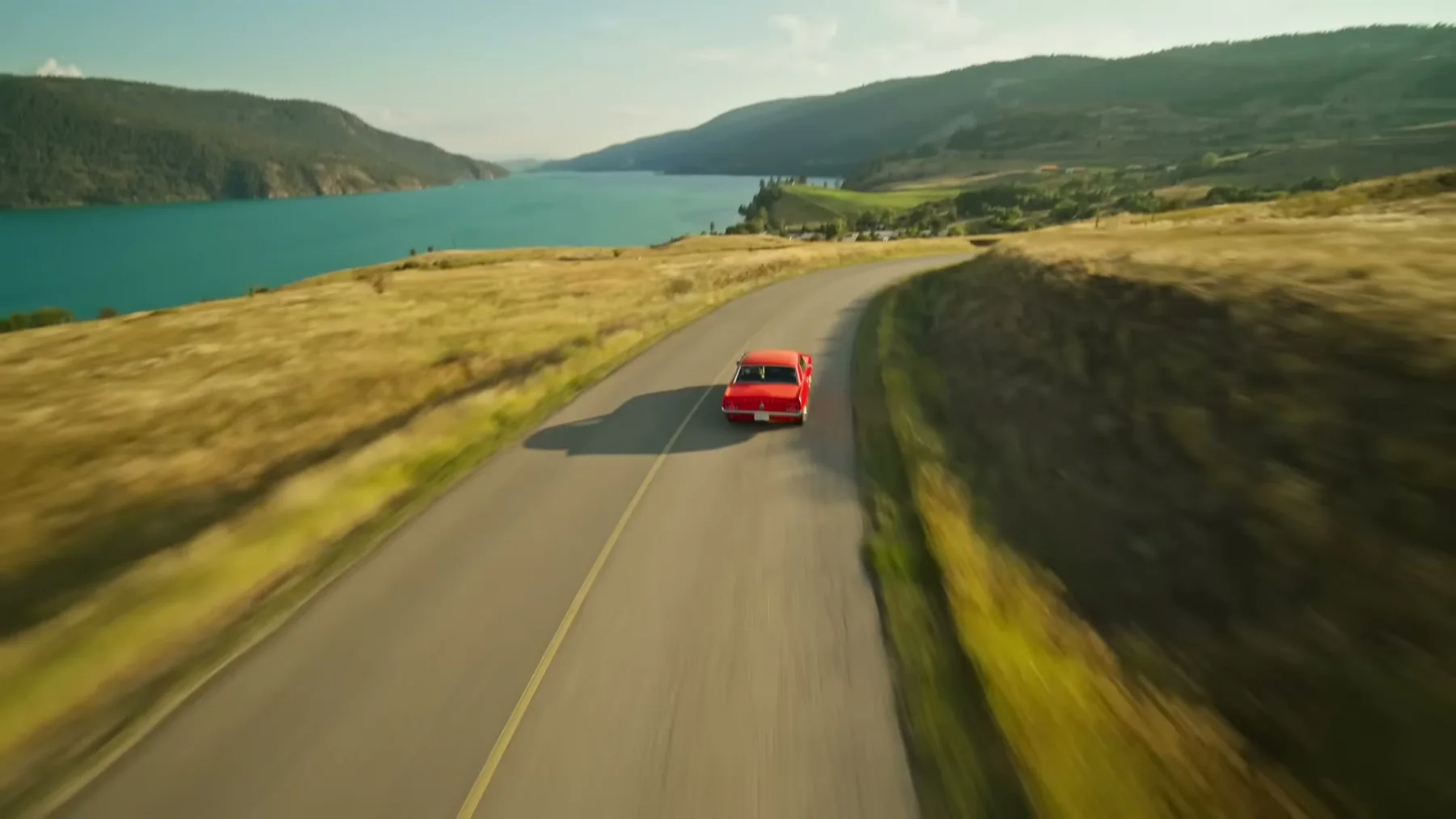 A red convertible travels along an Okanagan road beside a lake in Open Road.