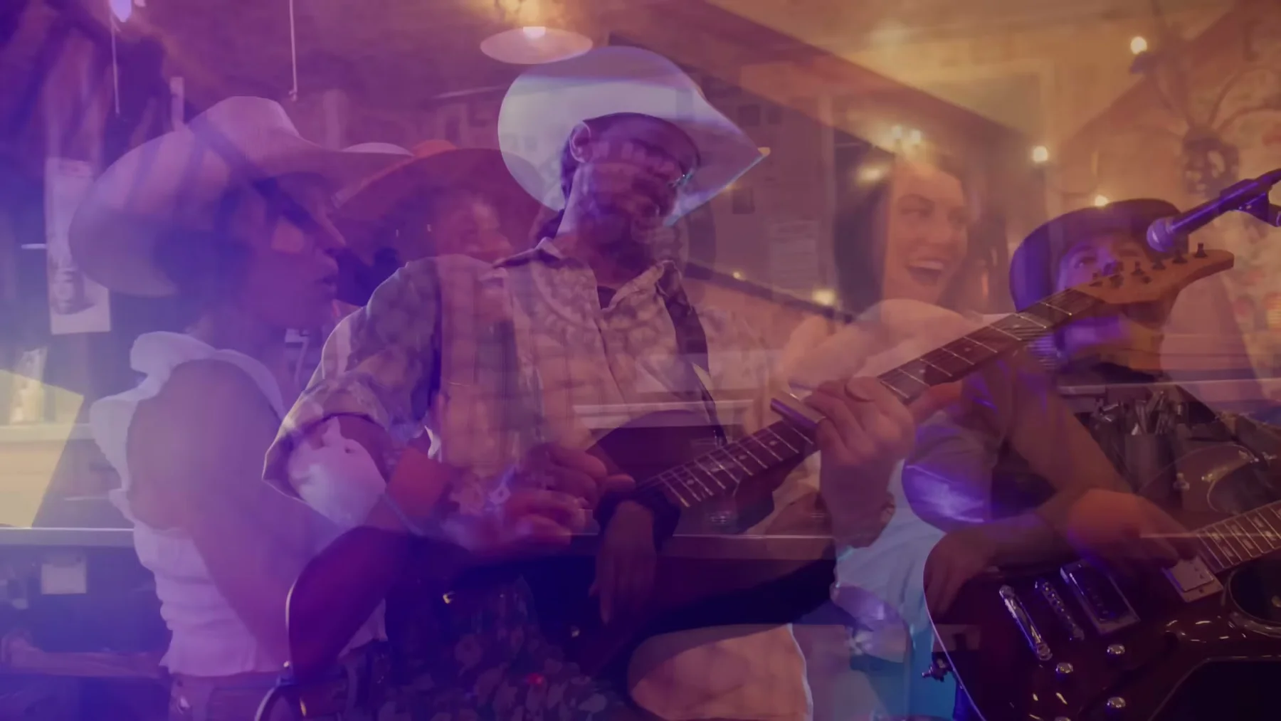 Kris Anders and his band perform under purple and amber light.