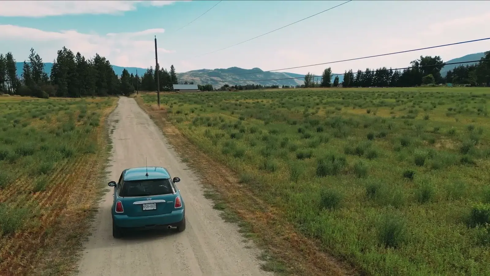 A car travels along a dirt road through Ridgeview Ranch fields.