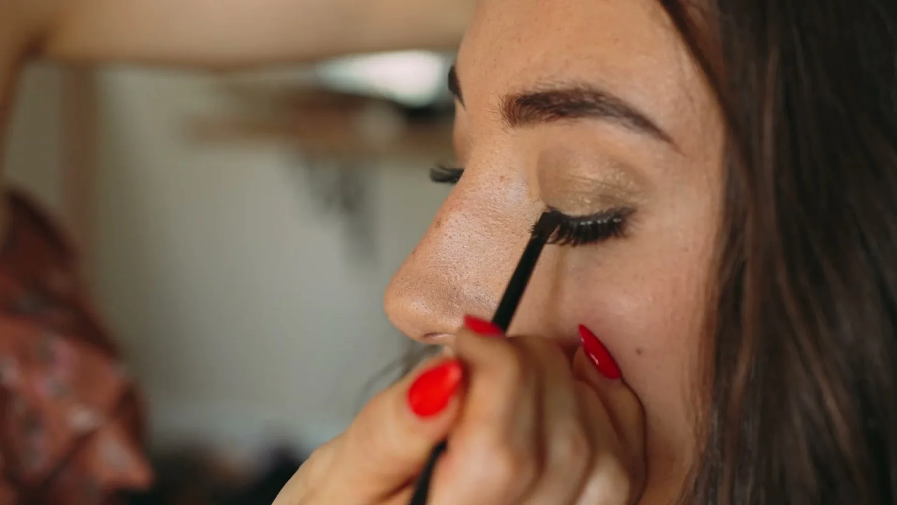 A bride has eye makeup applied before the ceremony.