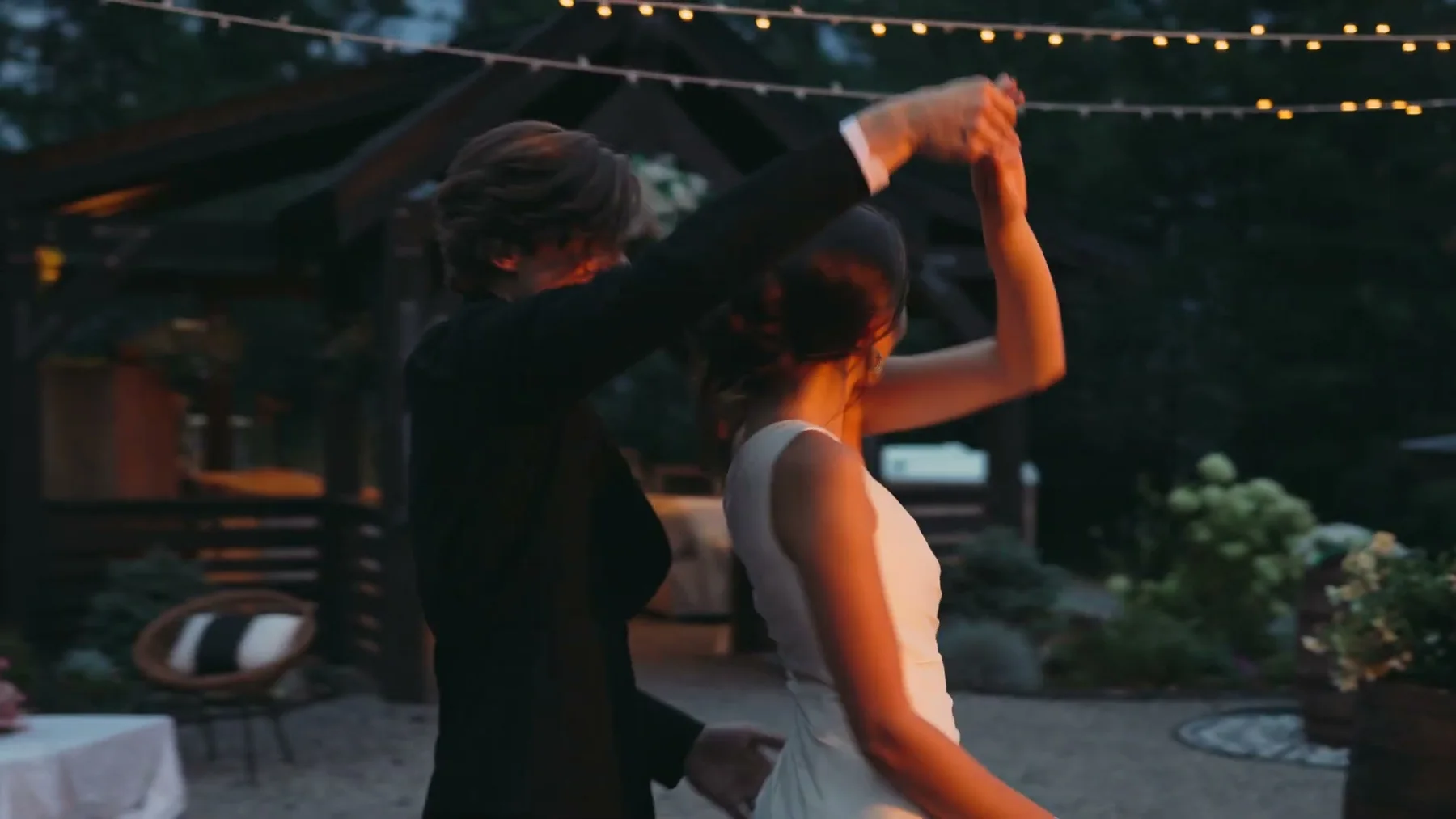 A groom turns the bride during an outdoor dance.