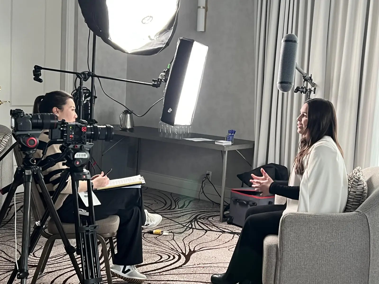 A camera films a seated woman during a SandBay conference interview.