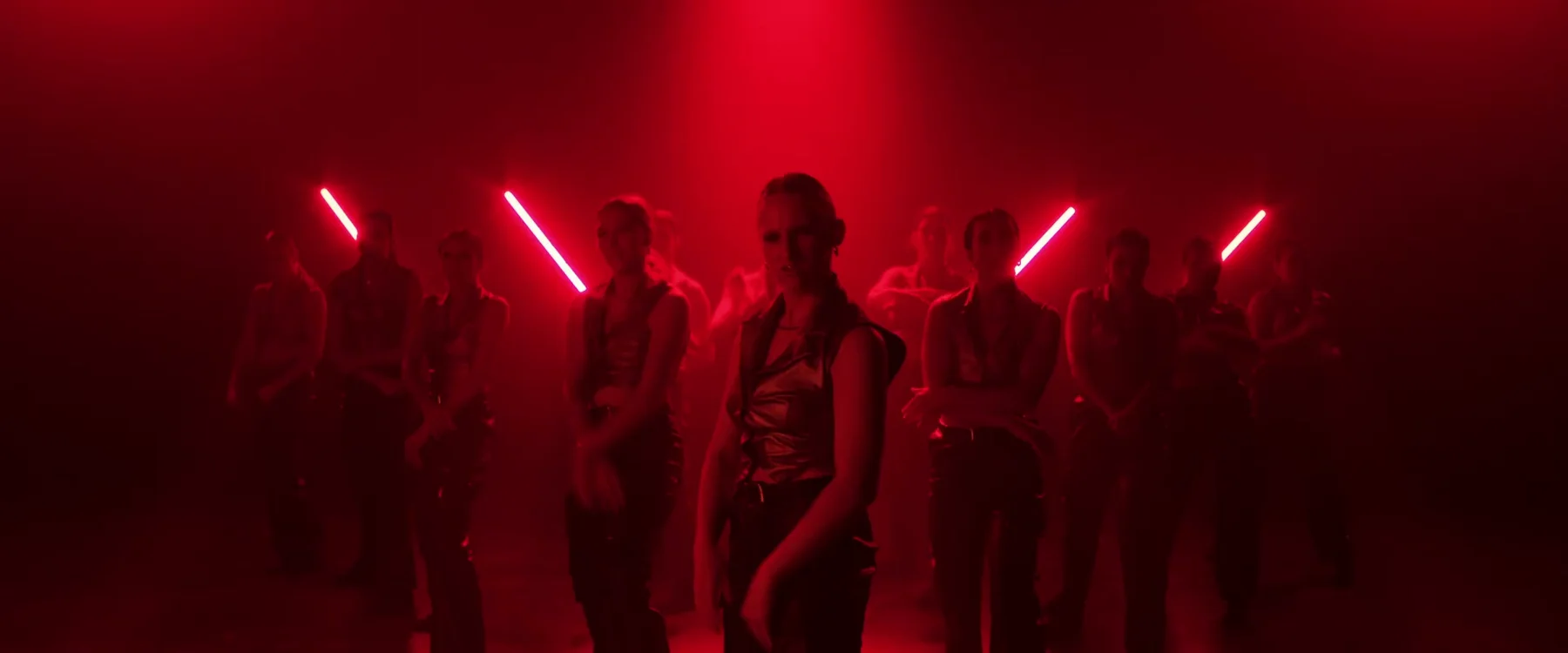 Sockeye 2024 ensemble holds a staggered formation in red stage light.