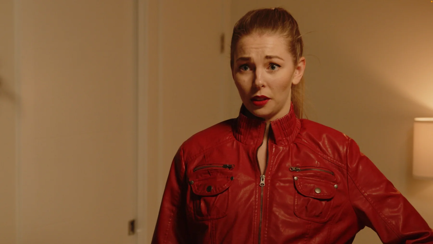 Actor in a red jacket inside a warm apartment scene from The Gift.