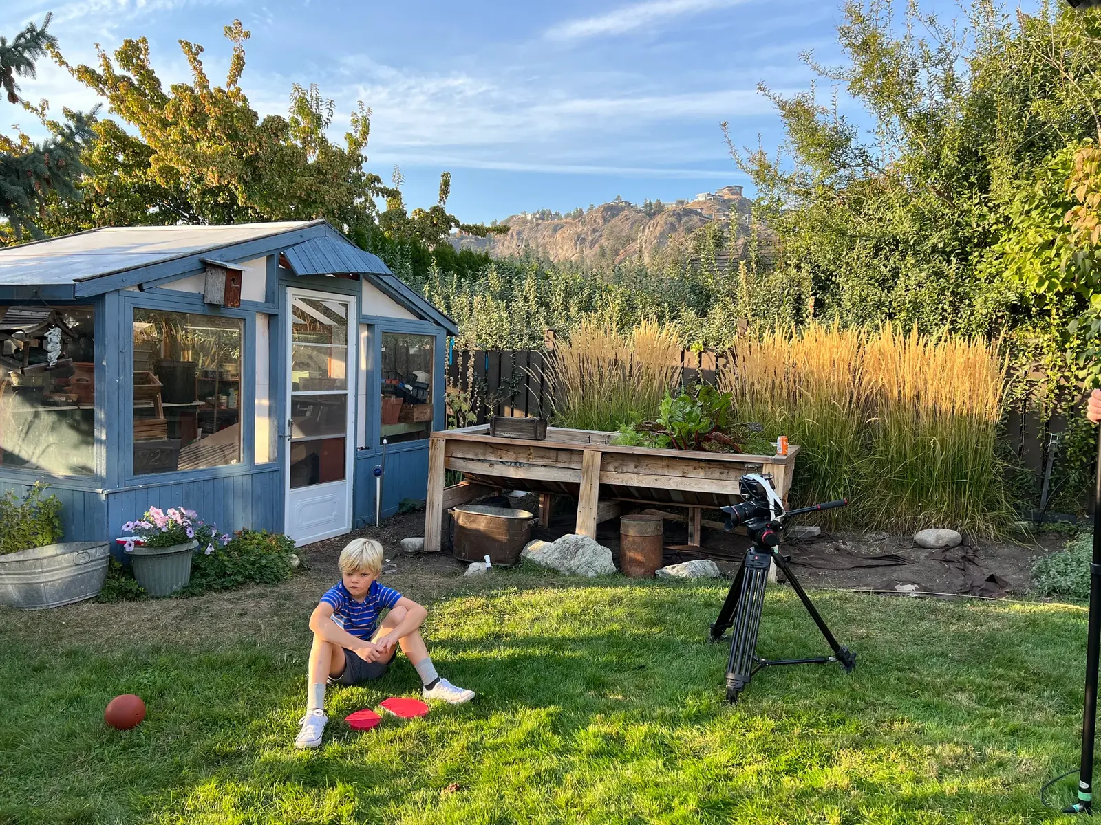 Wide yard BTS frame showing camera setup and young Dave during Three Hearts.