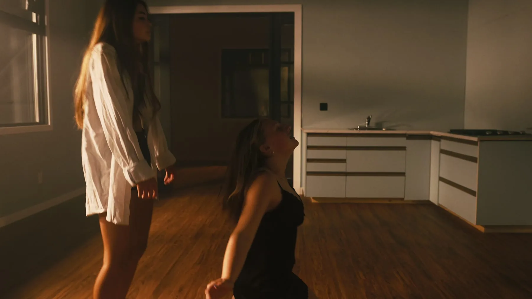 Two dancers move beside a couch in Vienna Hank's choreography film.