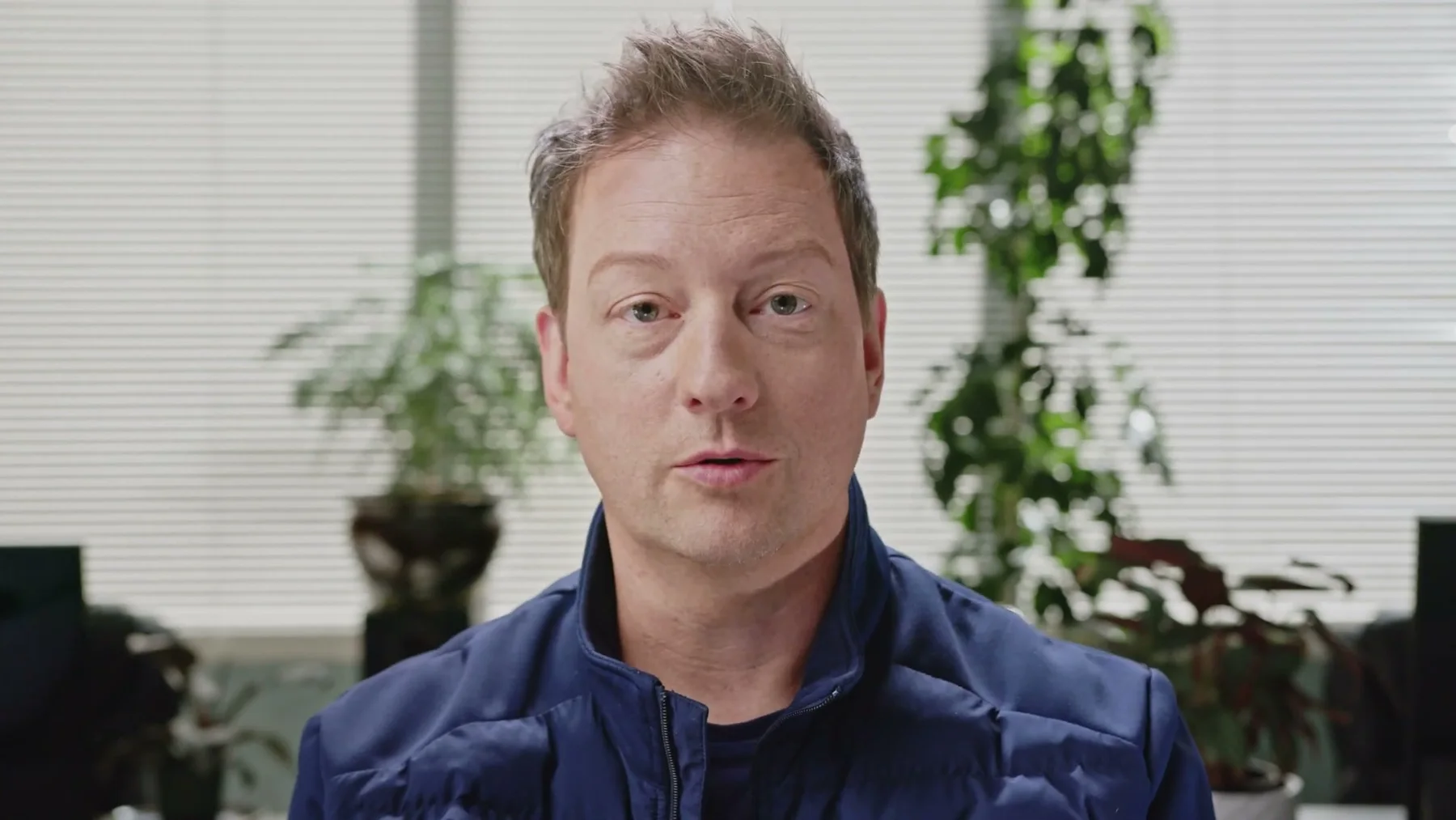 A Gneiss Stuff team member speaks in front of office plants.