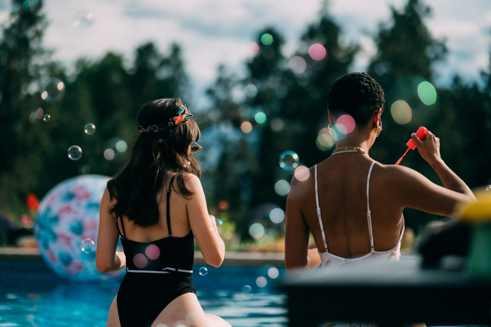 Zeff models blow bubbles beside a pool during golden-hour lifestyle photography.