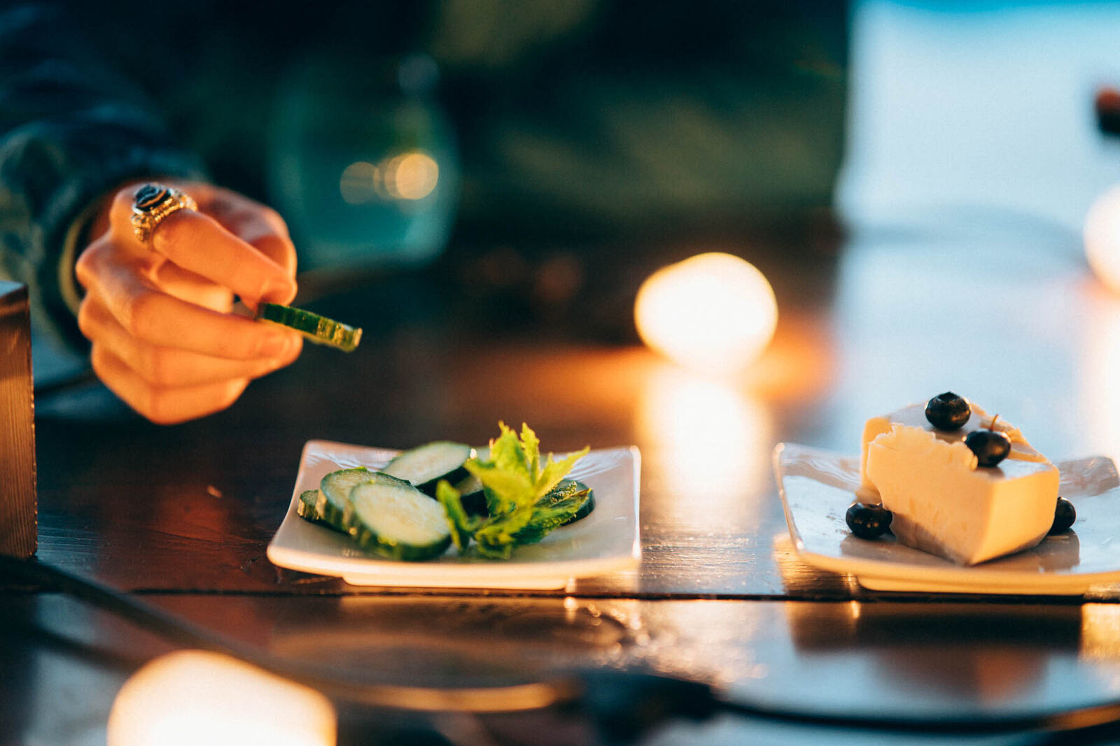A candlelit Zeff lifestyle table scene with drinks and plated food.